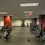 A gym with many machines and people in it