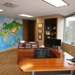 A room with a desk and chairs, a map on the wall.