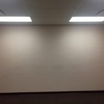 A white wall with lights on in an office.