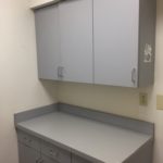 A gray cabinet in the corner of a room.