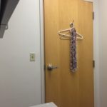 A door with a hanger on it and a scarf hanging from the handle.