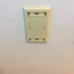 A white wall with a light switch on it