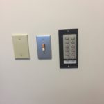 A wall with three different types of switches and controls.