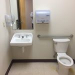 A bathroom with a toilet, sink and mirror.