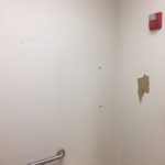 A bathroom wall with some holes in it