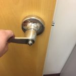 A person is holding the door handle of a room.