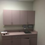 A kitchen with pink cabinets and white walls.