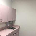 A pink kitchen with white walls and cupboards.