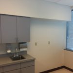 A kitchen with grey cabinets and white walls.