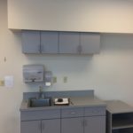 A kitchen with grey cabinets and a sink.