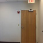 A door with an exit sign hanging on the wall.