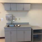 A kitchen with grey cabinets and a sink.