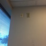 A room with two windows and a wall mounted phone.