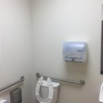 A bathroom with a toilet and a hand dryer.