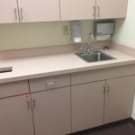 A kitchen with pink cabinets and white counters.