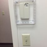 A white wall mounted device with a clear cover.