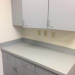 A white counter top with two cabinets and one door.