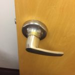 A door handle on the inside of a wooden door.