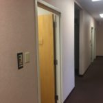 A hallway with two doors and a light brown wall.