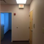 A hallway with an exit sign on the wall.