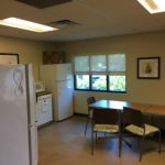 A kitchen with a refrigerator, table and chairs.