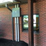 A brick building with a window and a metal pole.