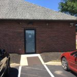 A red car parked in front of a brick building.